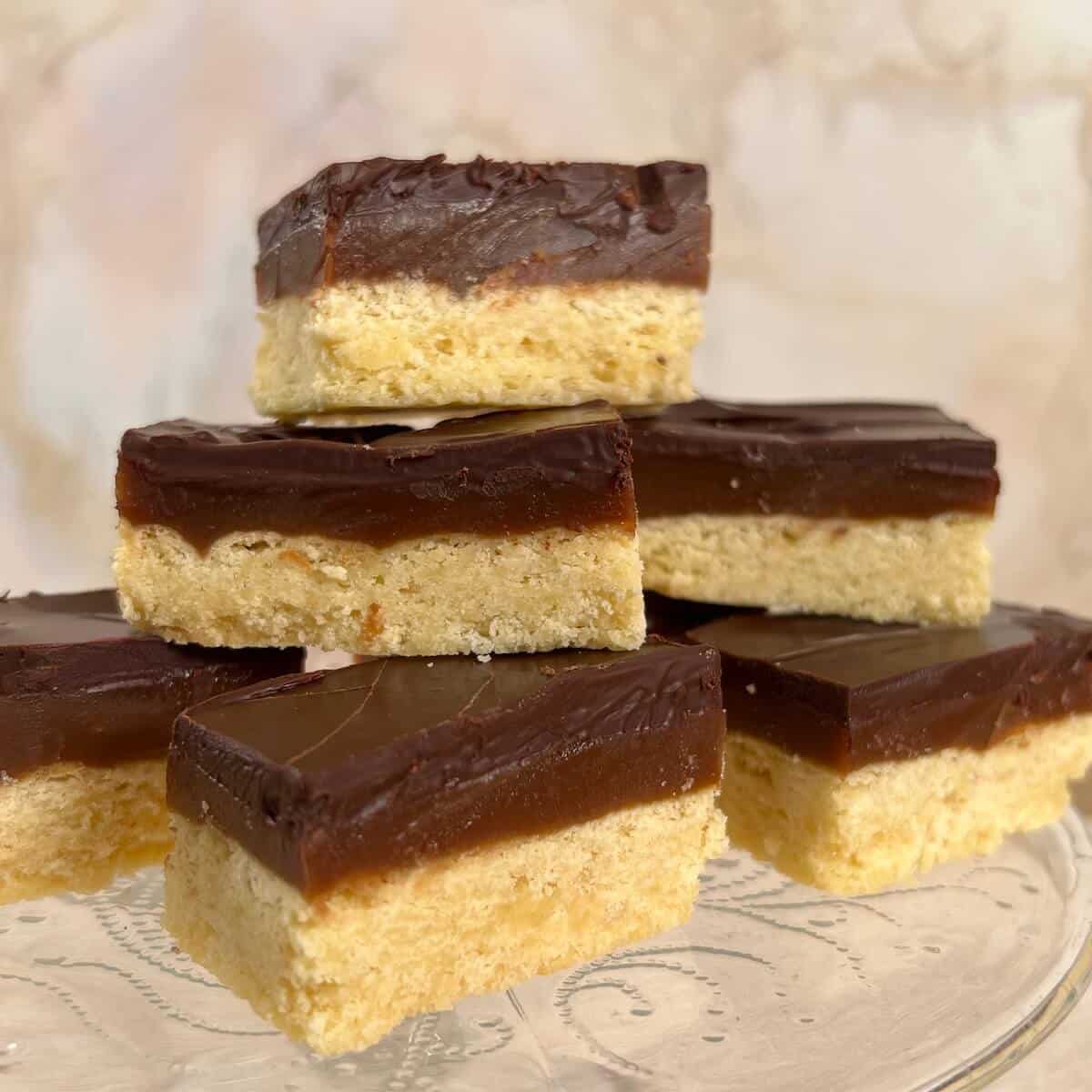 A stacked pile of Millionaire's Shortbread on a glass cake stand.