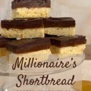 A stacked pile of Millionaire's Shortbread on a glass cake stand with chocolate coins below Pinterest banner.