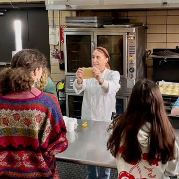 Tammy demonstrating to a class how to see if challah dough is kneaded enough by stretching it.