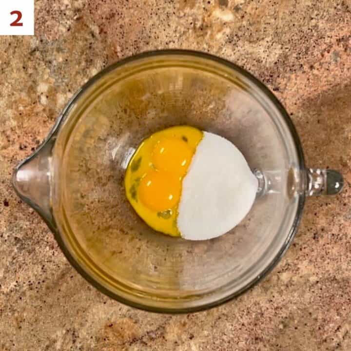 Egg yolks and sugar in a glass bowl.