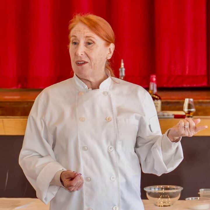 Tammy holding a class of bourbon while lecturing about tasting spirits.