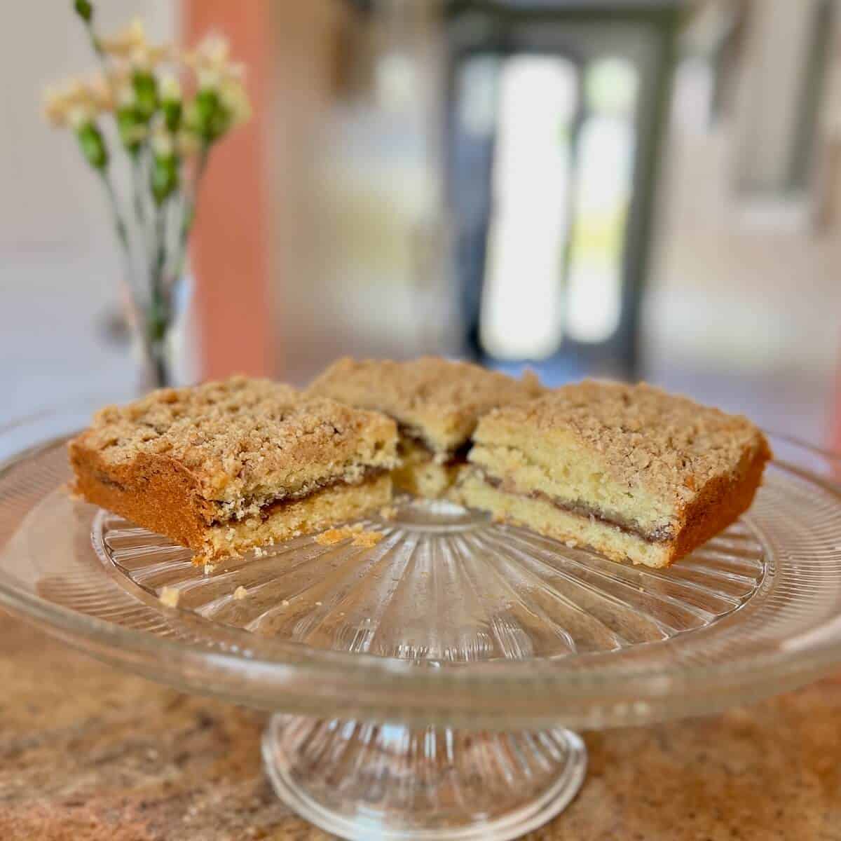 Squares of Sourdough Discard Tahini Coffee Cake on a glass cake stand.