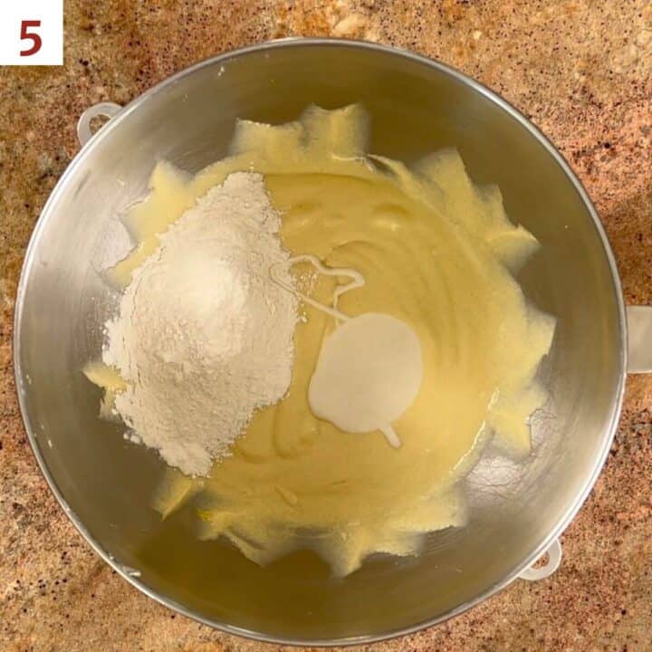 Adding the flour mixture to the cake batter in a metal mixing bowl.