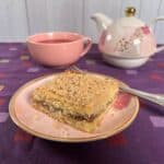 Sourdough Discard Tahini Coffee Cake and a fork on a pink plate with a pink teacup and teapot behind it.