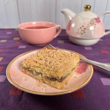Sourdough Discard Tahini Coffee Cake and a fork on a pink plate with a pink teacup and teapot behind it.