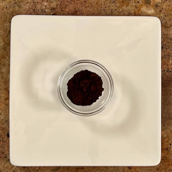 Vanilla bean powder in a glass bowl on a white plate.
