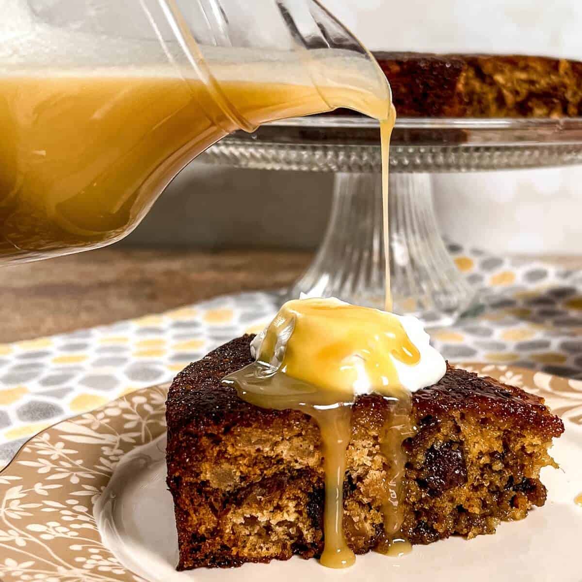 Pouring toffee sauce onto a slice of sticky toffee pudding on a plate.