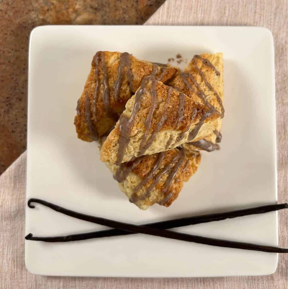 Vanilla Bean Scones on a white plate with 2 crossed vanilla beans.