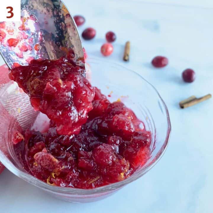 Cooked cranberry sauce dripping from a spoon.